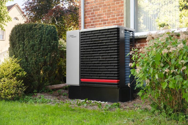 Wärmepumpe im Garten neben einem Einfamilienhaus